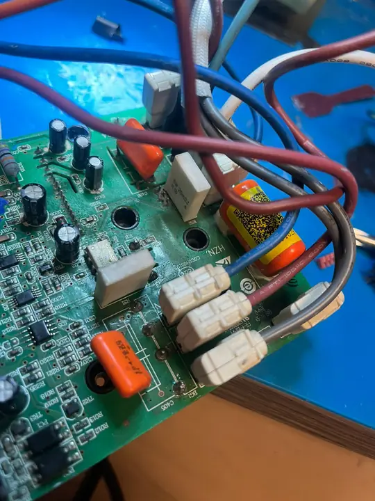 Primer plano de una tarjeta inverter con capacitores electrolíticos, capacitores de poliéster y conectores con cables de alimentación